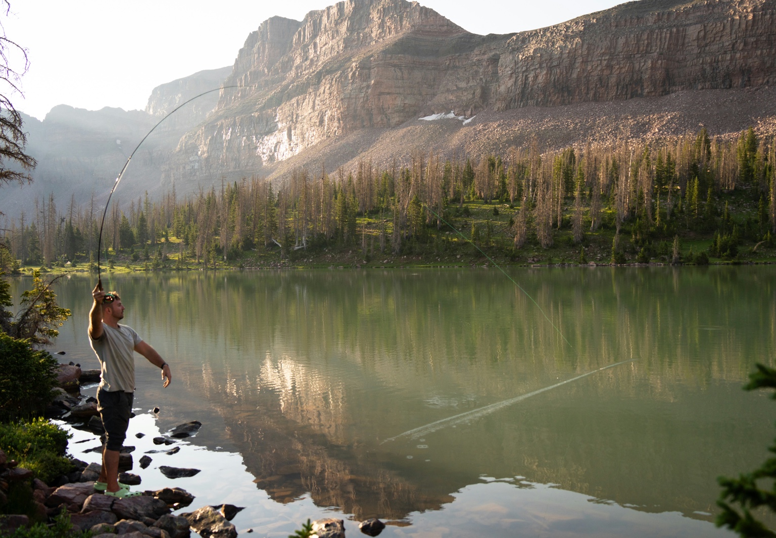 Man casting into alpine lake
