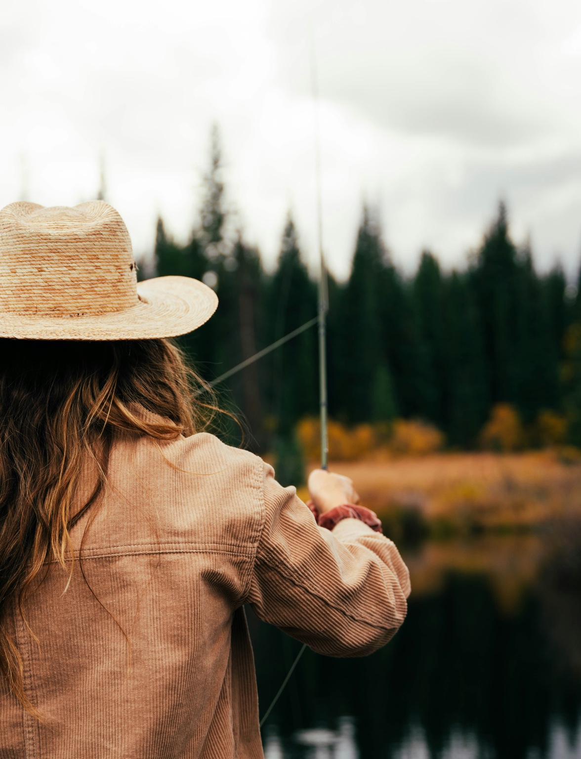 Woman fly fishing in hat - lifestyle image